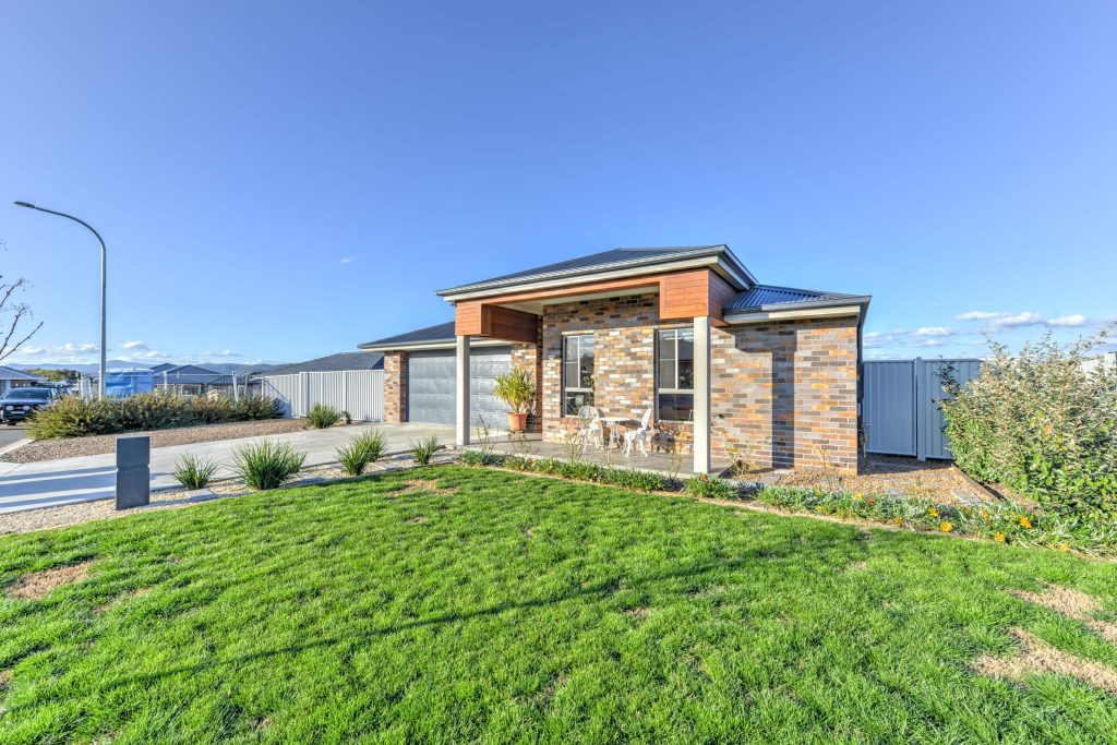 Custom Home Builder Tamworth: front exterior of a custom-built home in Hillvue, NSW, with brick façade, dark roof, double garage and landscaped lawn.